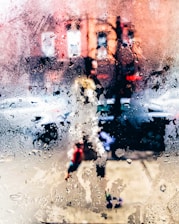 photo of moistened glass with view of person walking on pathway