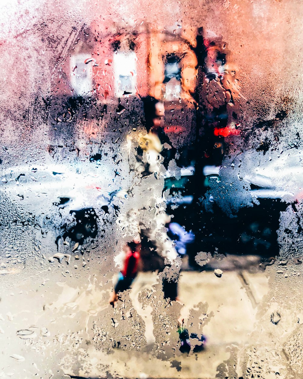 photo of moistened glass with view of person walking on pathway