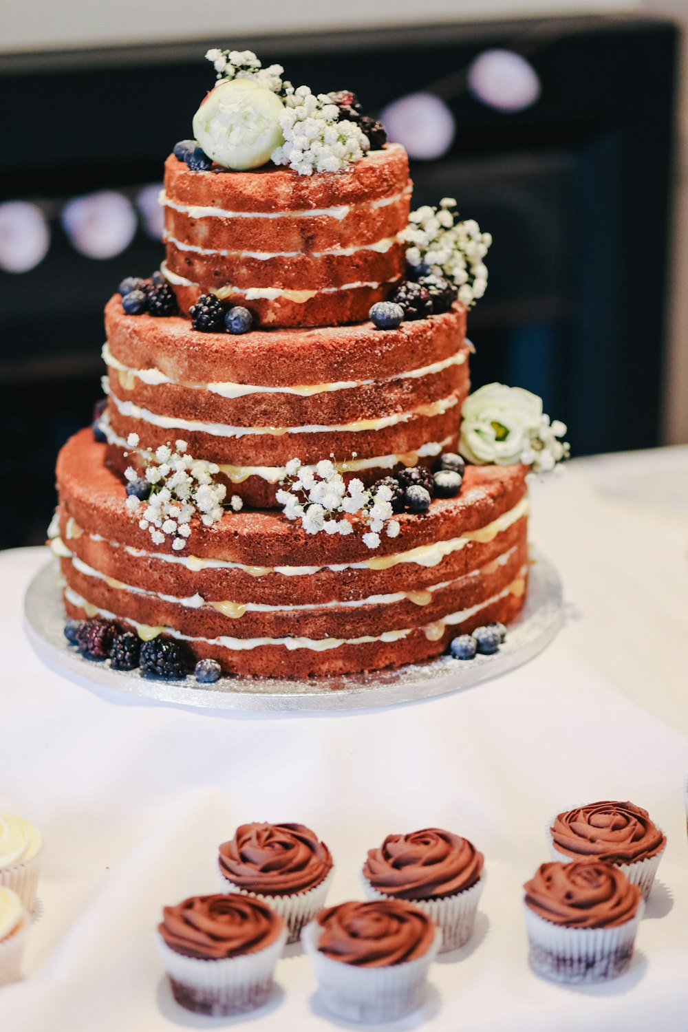 gâteau recouvert de glaçage à côté des cupcakes