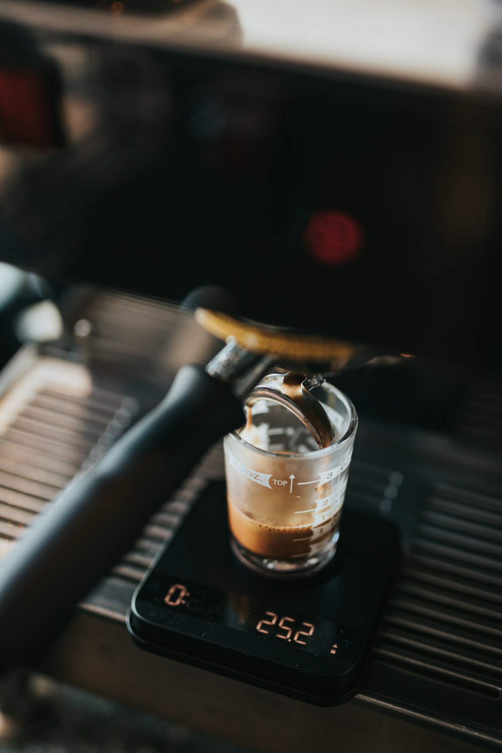 Foto de primer plano de la cafetera espresso negra que archiva la taza de vidrio transparente