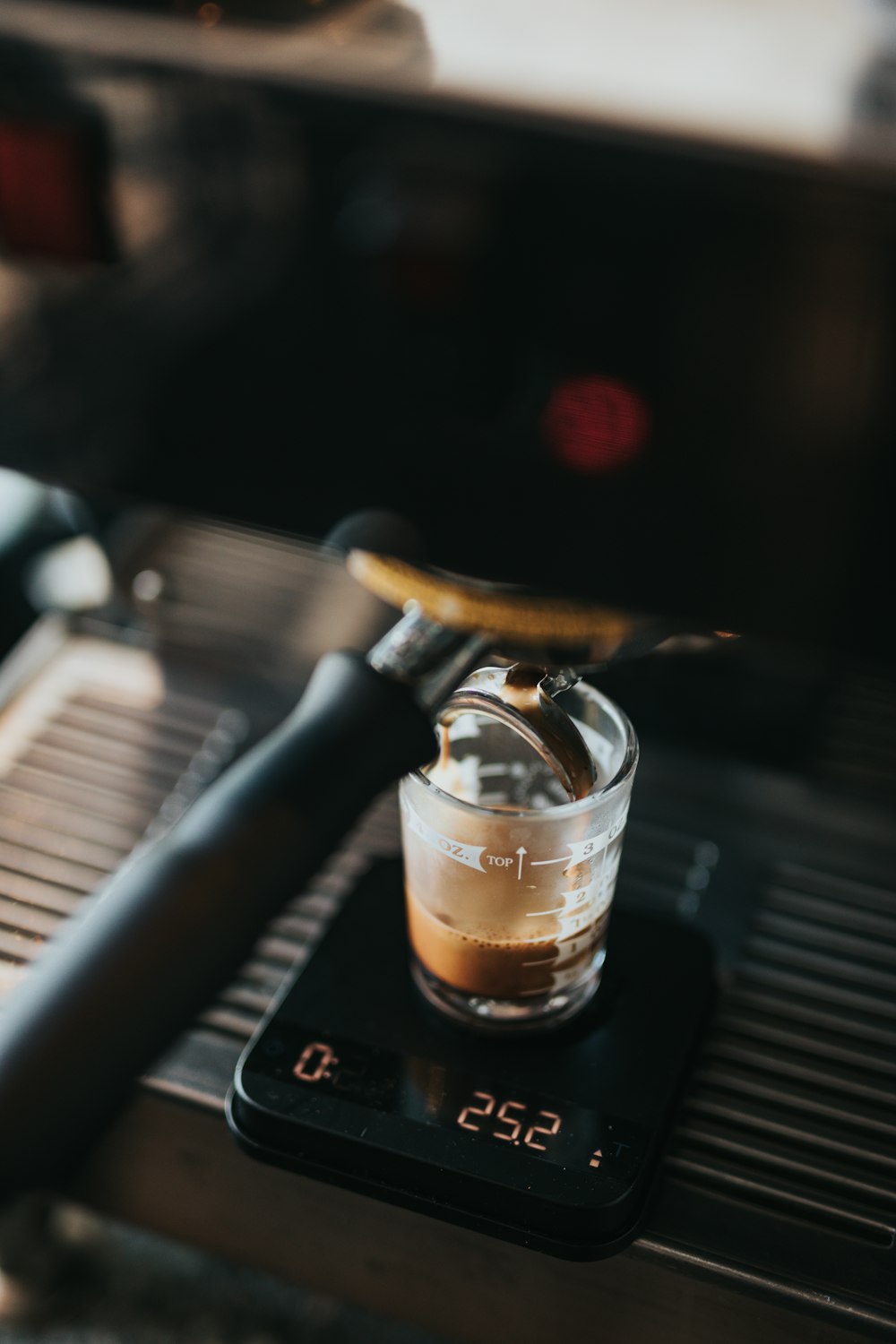 photo en gros plan d’une machine à expresso noire limant une tasse en verre transparent