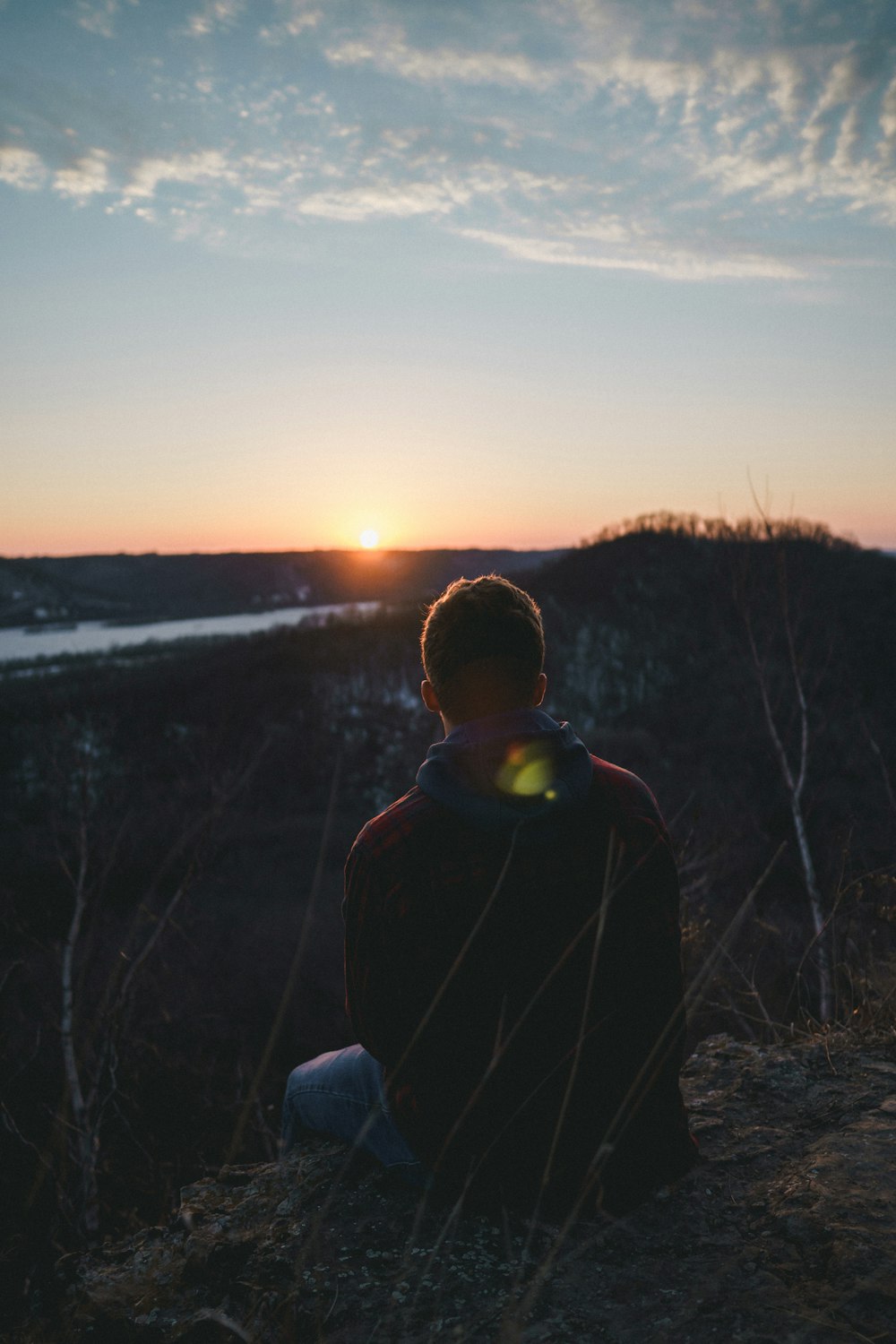 man sitting on grass facing forward on mountain