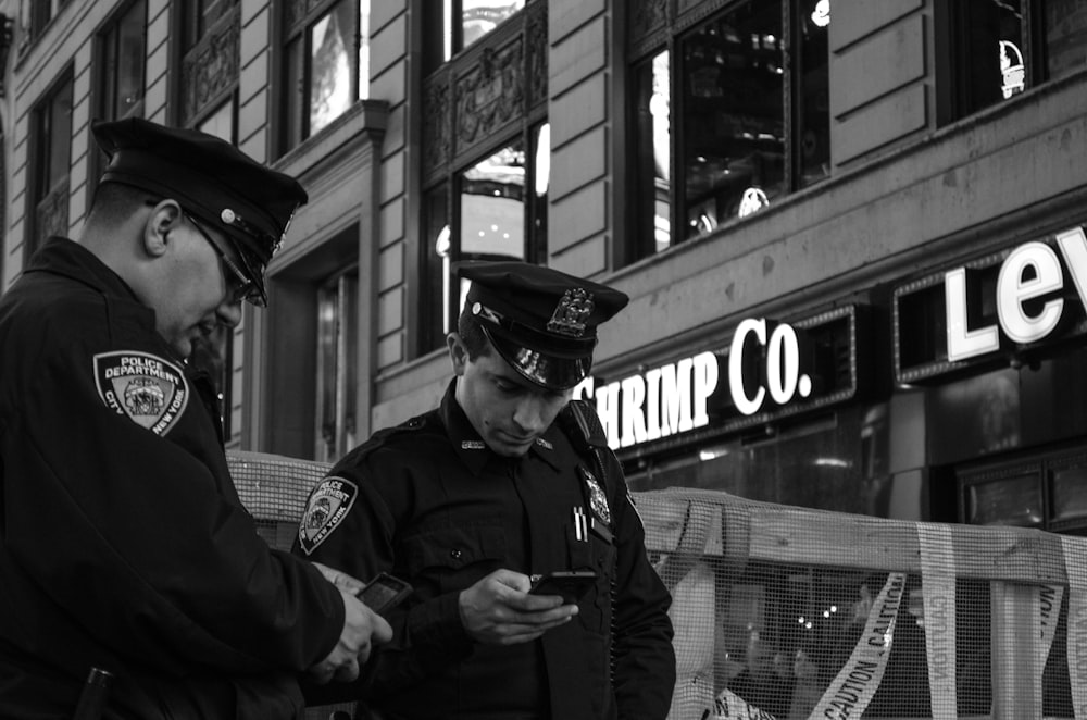 grayscale photo of two policemen standing near store