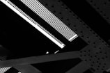 Detailed view of a steel structure with intersecting girders and a grated surface, showing patterns of bolts and rivets.