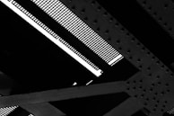 Detailed view of a steel structure with intersecting girders and a grated surface, showing patterns of bolts and rivets.