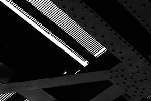 Detailed view of a steel structure with intersecting girders and a grated surface, showing patterns of bolts and rivets.