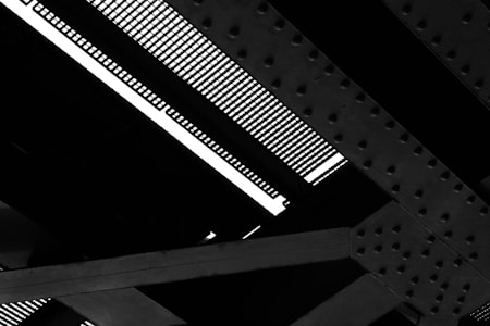 Detailed view of a steel structure with intersecting girders and a grated surface, showing patterns of bolts and rivets.