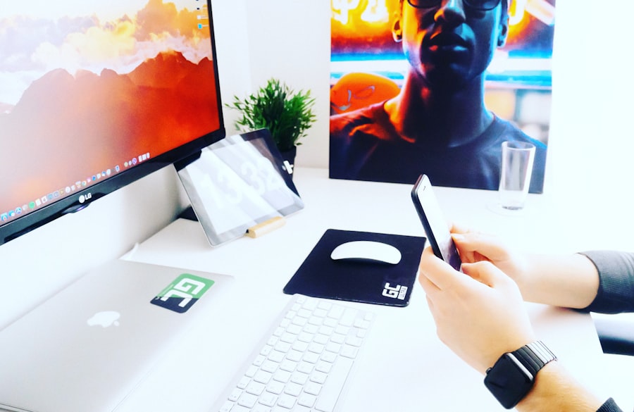Personne en télétravail tenant son smartphone près d'un moniteur, illustrant la posture à corriger