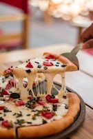 Close-up of a cheesy pizza slice being lifted from the pie.