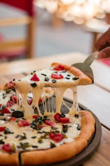 Close-up of a pizza slice being lifted, cheese stretching with warm oven glow.
