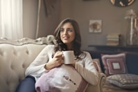 woman holding mug sitting on sofa