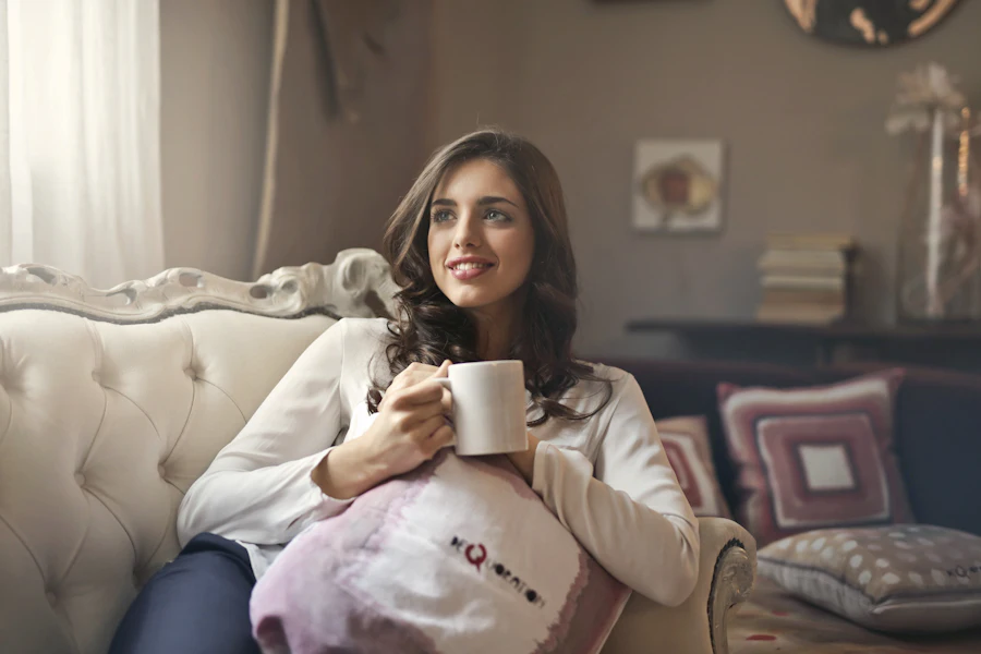 Mulher em um momento de pausa, segurando uma caneca no sofá