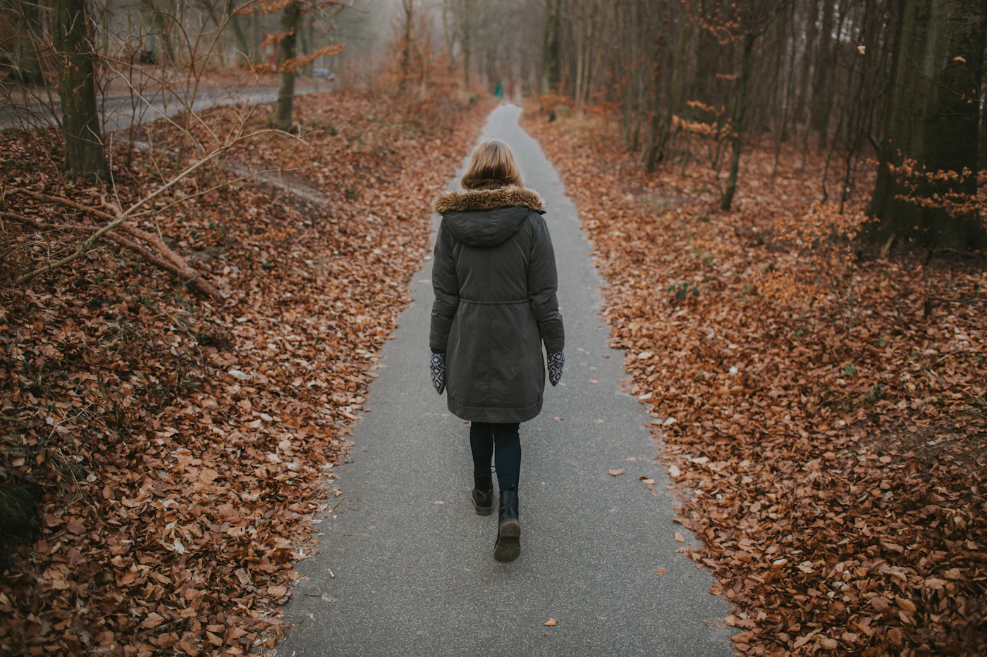 Frau geht allein auf einem Waldweg als Symbol für Abstand und Stressabbau ohne Zigarette