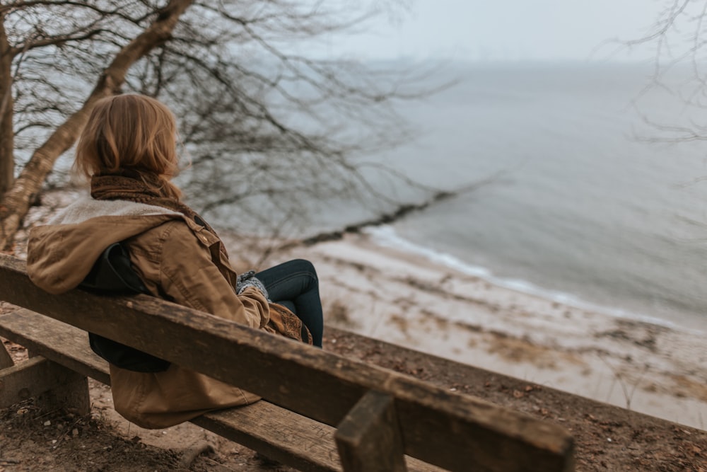 woman sitting on brown wooden bench