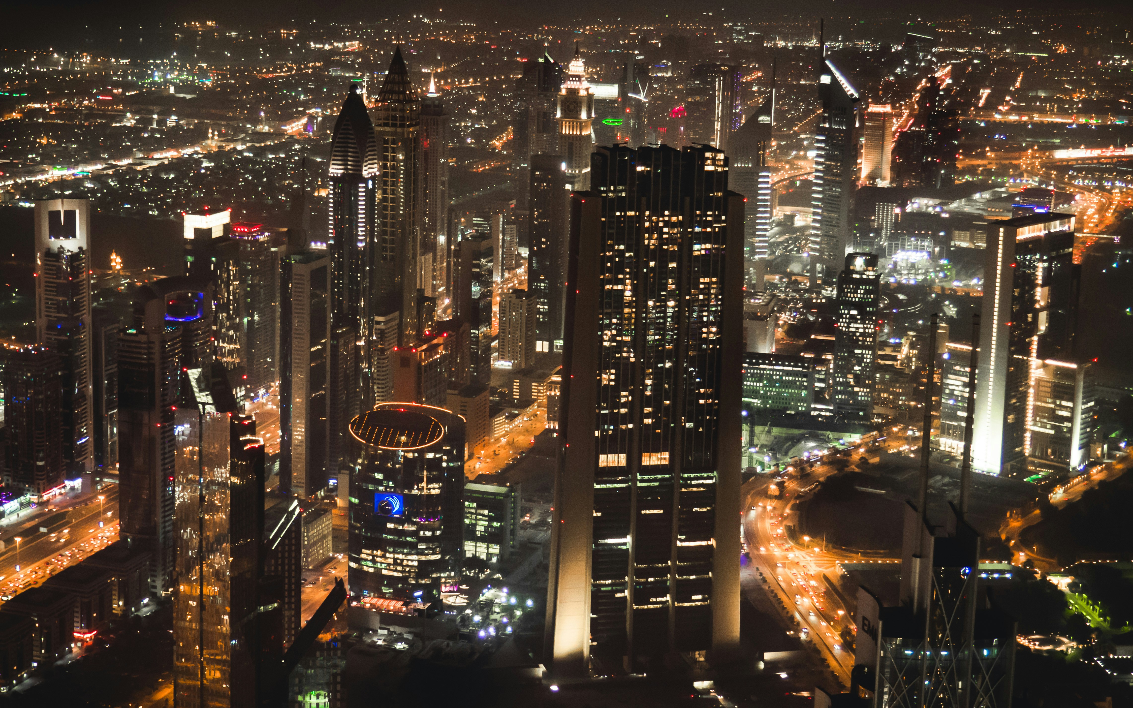 Aerial night view of city skyline with glowing lights, deep navy sky, dramatic urban atmosphere, dense skyscrapers