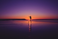 A couple laughing while watching the sunset from a quiet beach cove.