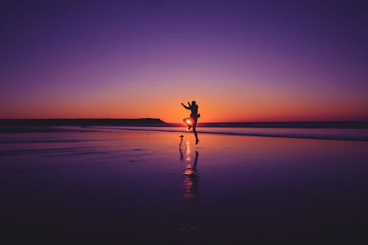 A sunlit candid moment of a couple laughing together on a sandy beach, with warm terracotta hues glowing around them.