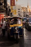 man standing beside yellow auto rickshaw