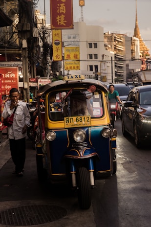 man standing beside yellow auto rickshaw