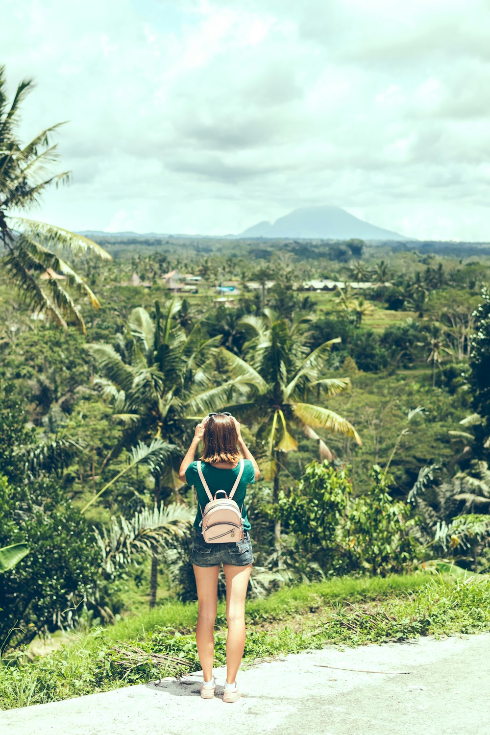 woman standing at front of green trees under cloudy sky during daytime