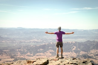 man stand on brown mountain under blue sky