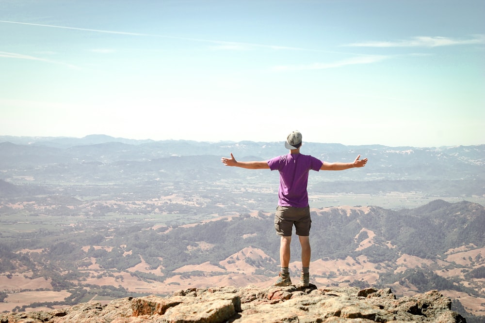 homme debout sur la montagne brune sous le ciel bleu