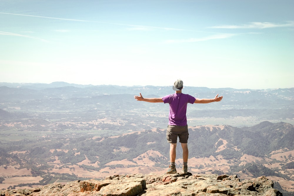 man stand on brown mountain under blue sky