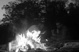 High-contrast night image of bikers around a campfire sharing stories and laughs