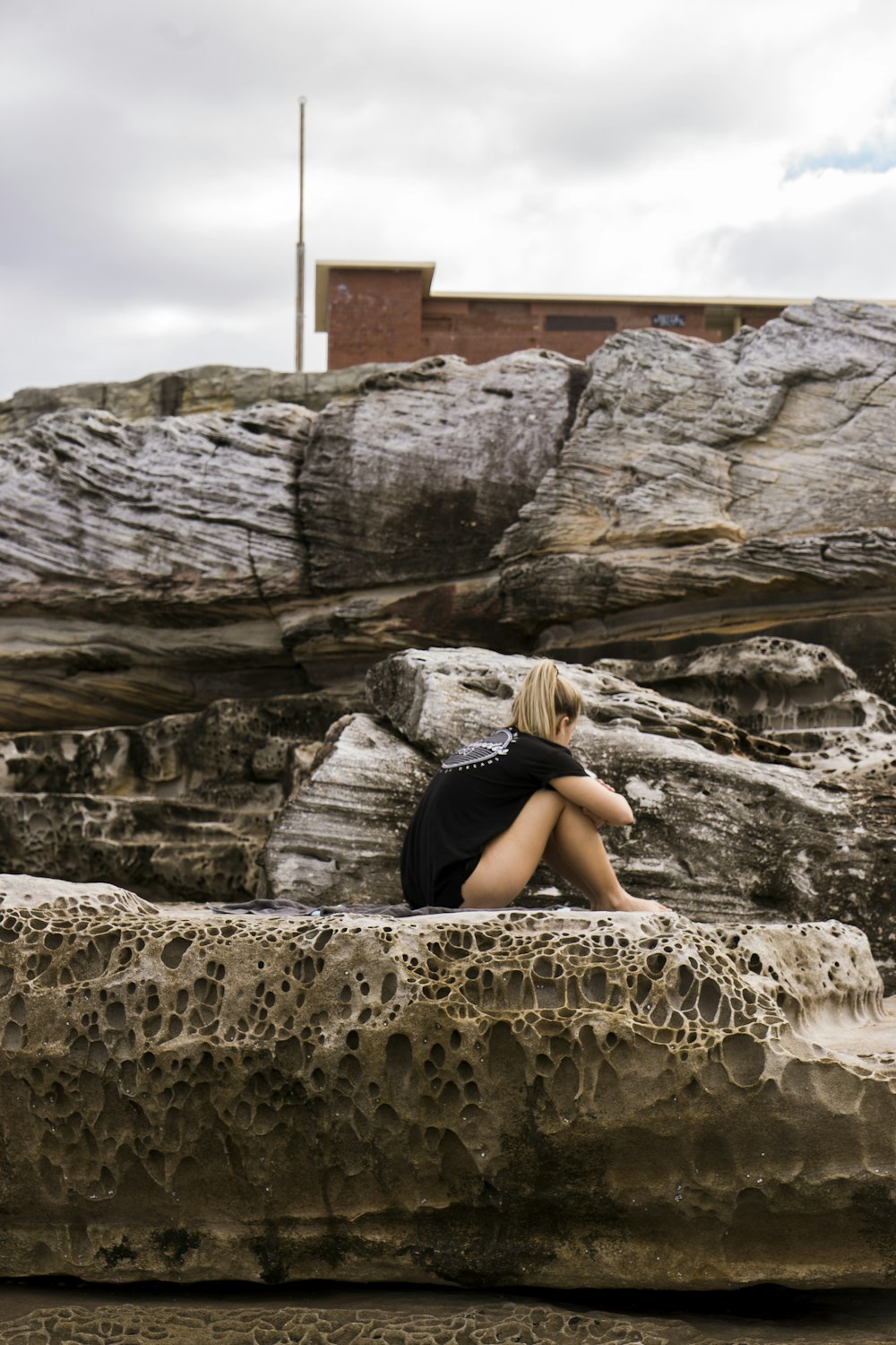 야외에서 회색 암석에 앉아있는 여자