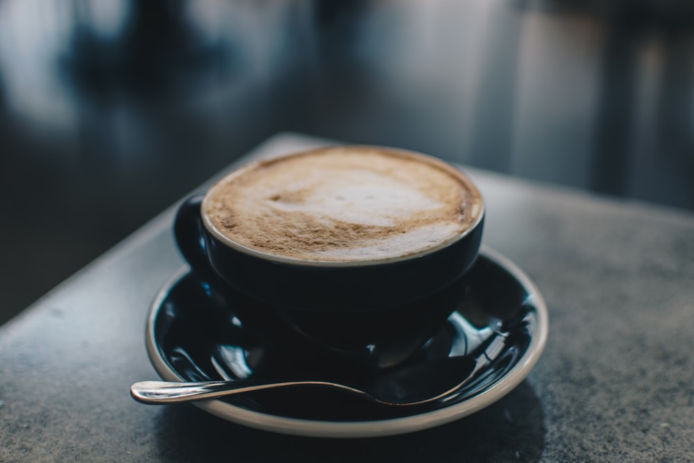 photo of black teacup filled with coffee on saucer