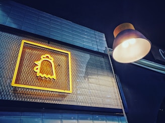 Belab holding a glowing sign that reads 'yo soy belab' surrounded by warm earth tones and golden light.