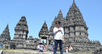 Mao guiding a small group through the intricate carvings of Bayon temple under a bright blue sky.