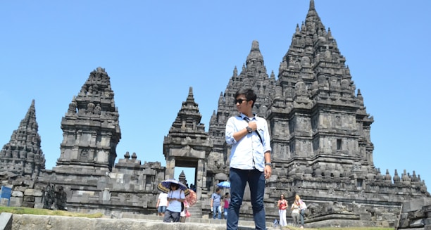 Mao guiding a small group through the intricate carvings of Bayon temple under a bright blue sky.