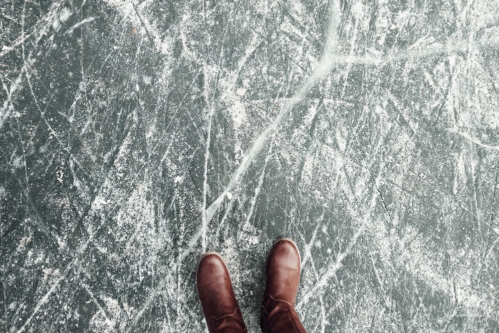 closeup photo of person's food wearing boots on gray pavement