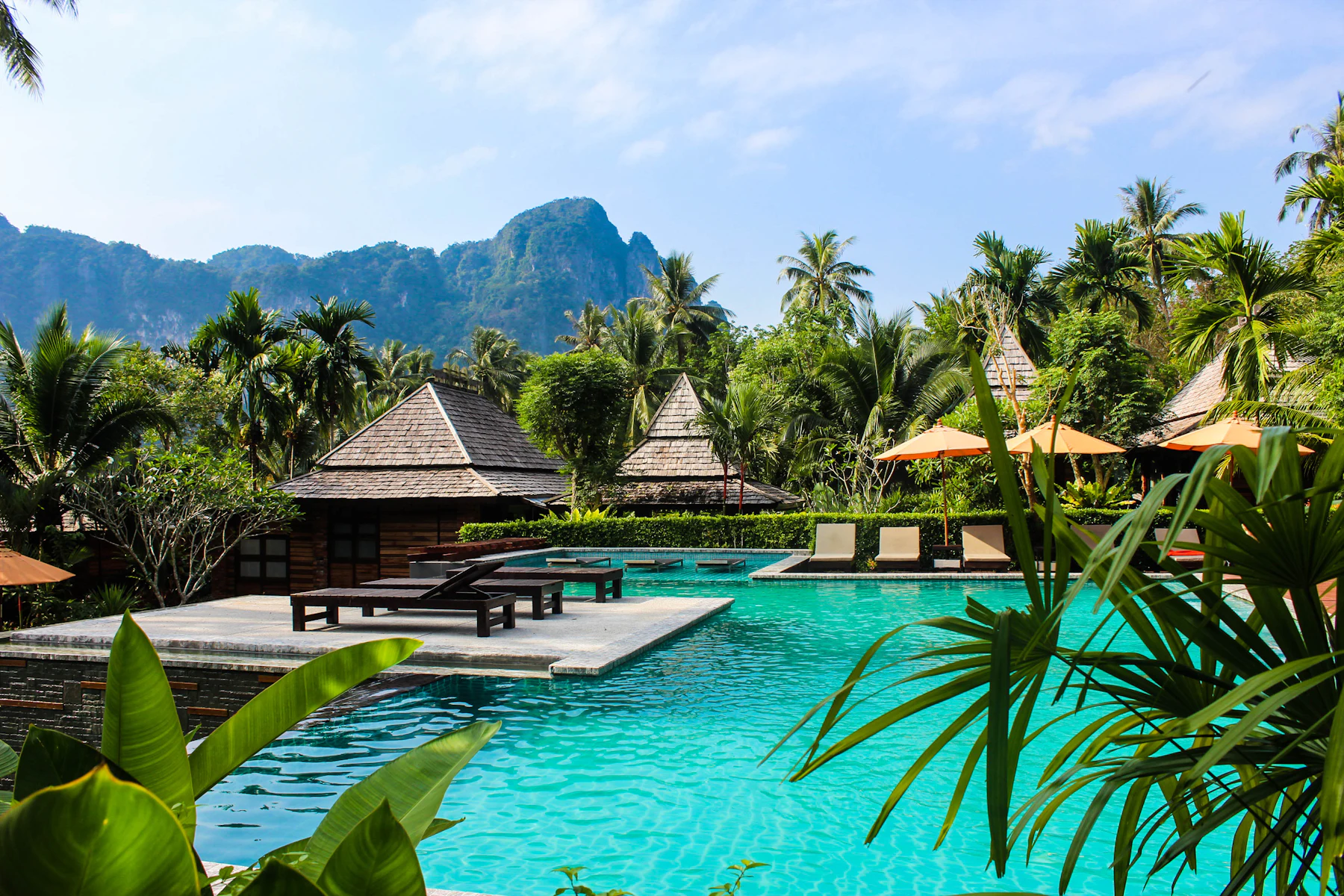 A thatched pavilion beside a pool below limestone cliffs