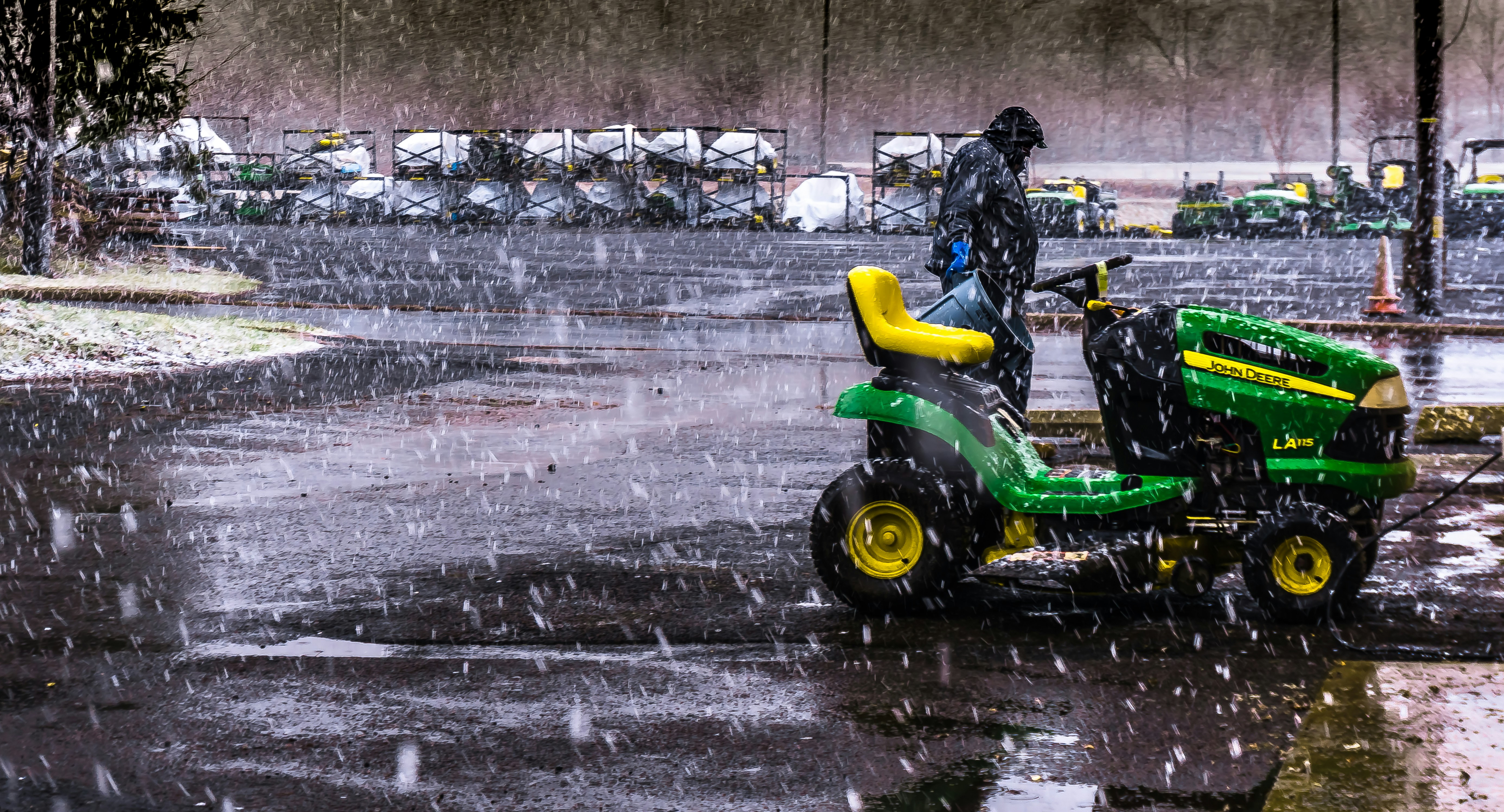 Rain falling on a green lawn with a mower parked in a garage