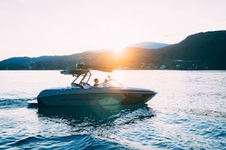 A friendly technician working on a boat engine beside a peaceful marina at sunset.