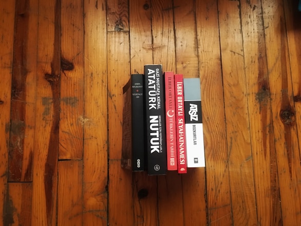 A stack of colorful e-books on a wooden desk.