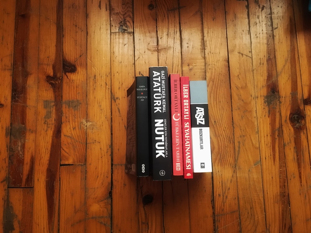 top angle-view of five assorted-title books on brown wooden plank surface
