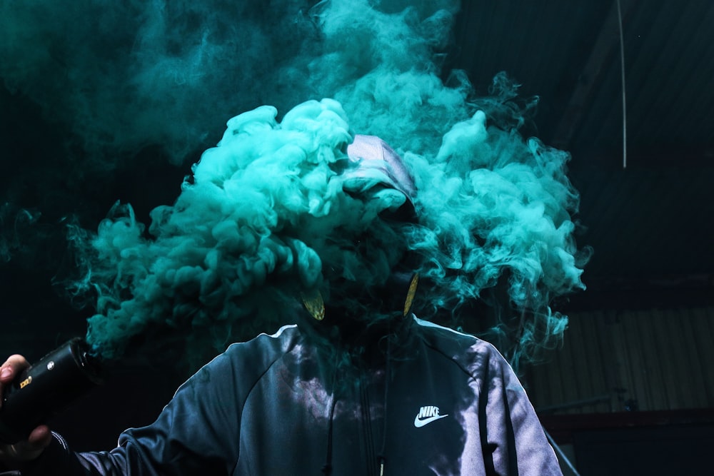 Foto einer Person, die eine türkisfarbene Rauchgranate hält