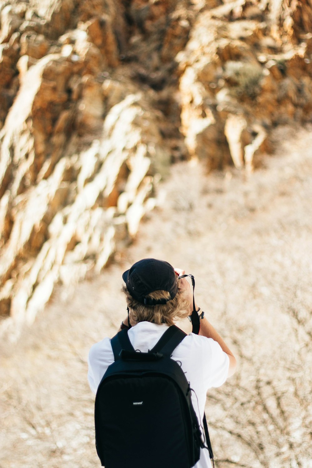 man taking photo of brown rocky mountains