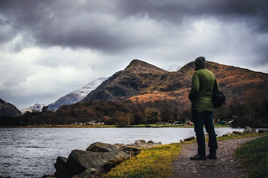 man standing on ground facing body of w ater in Llanberis United Kingdom