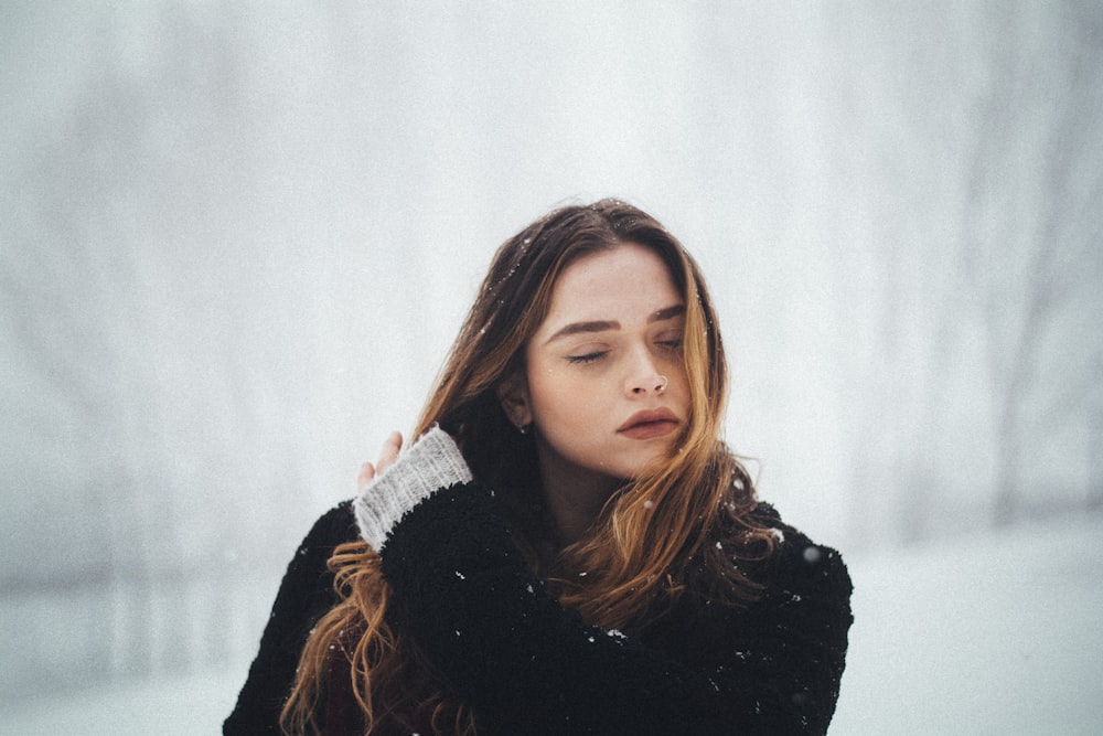 woman wearing black coat holding her hair