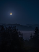A glowing full moon over a quiet landscape, symbolizing lunar cycles and inner listening.