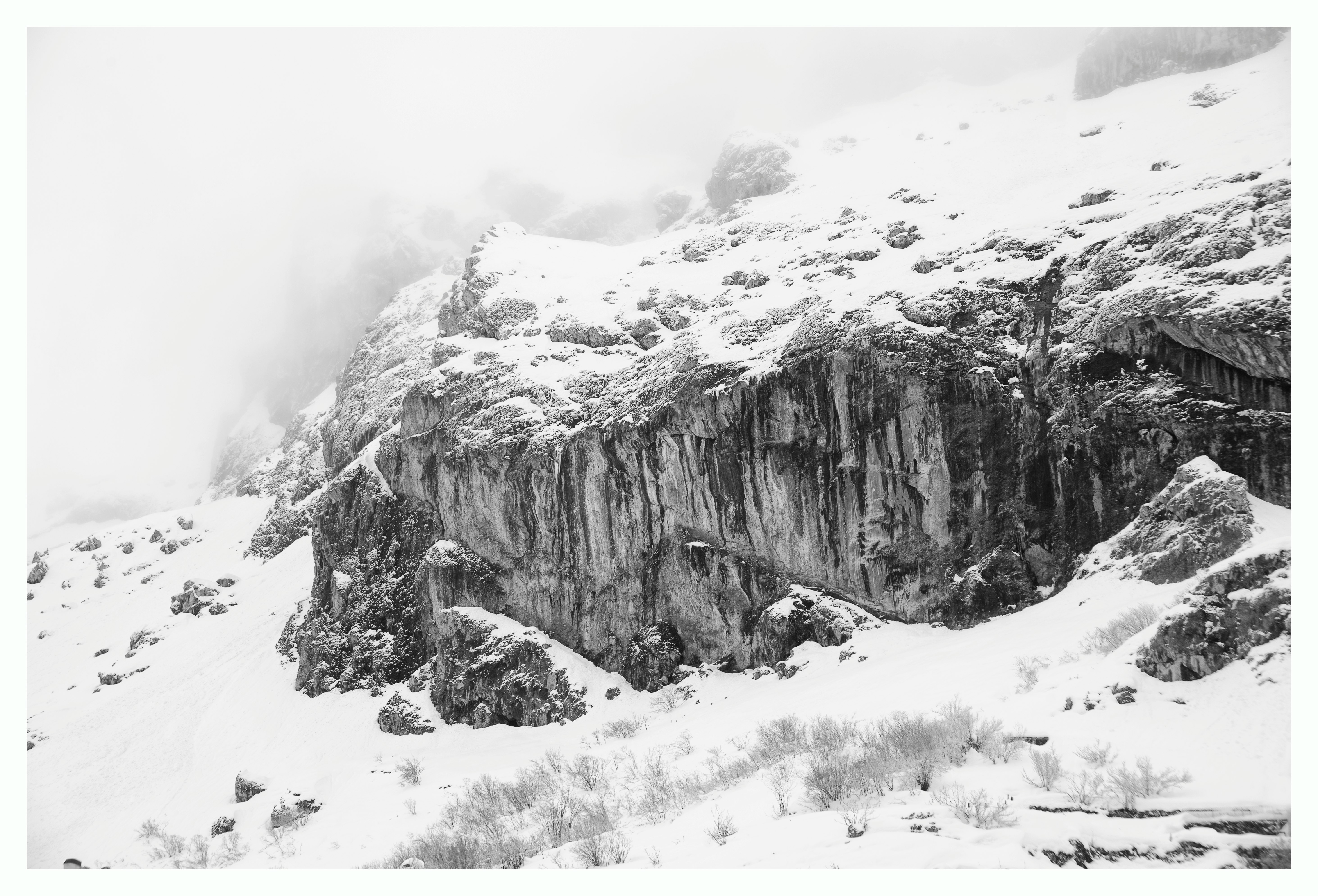 grayscale photography of snow covered cliff