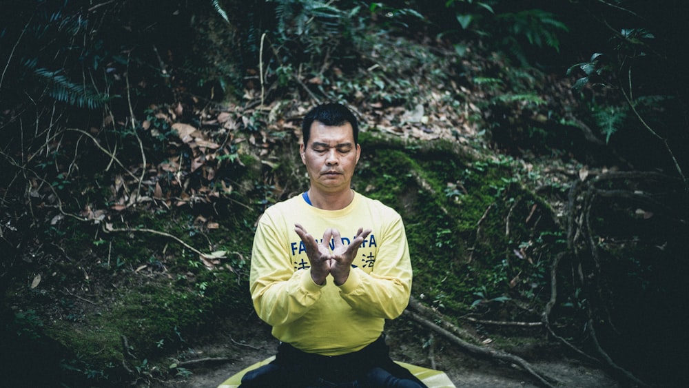 man meditating under forest