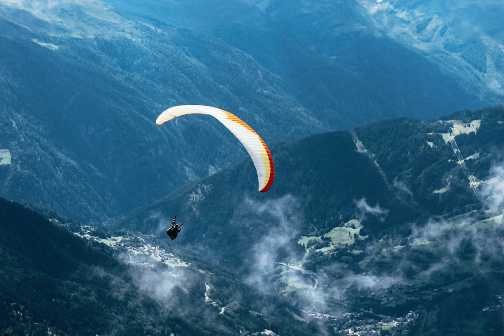Persona volando en parapente sobre cadenas montañosas