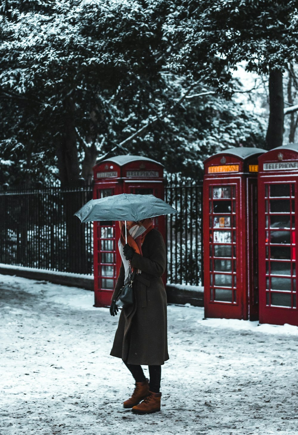 Mulher sob o guarda-chuva perto da cabine telefônica