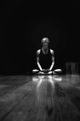 A focused man meditating in a dark, minimalist room symbolizing discipline and mental clarity.