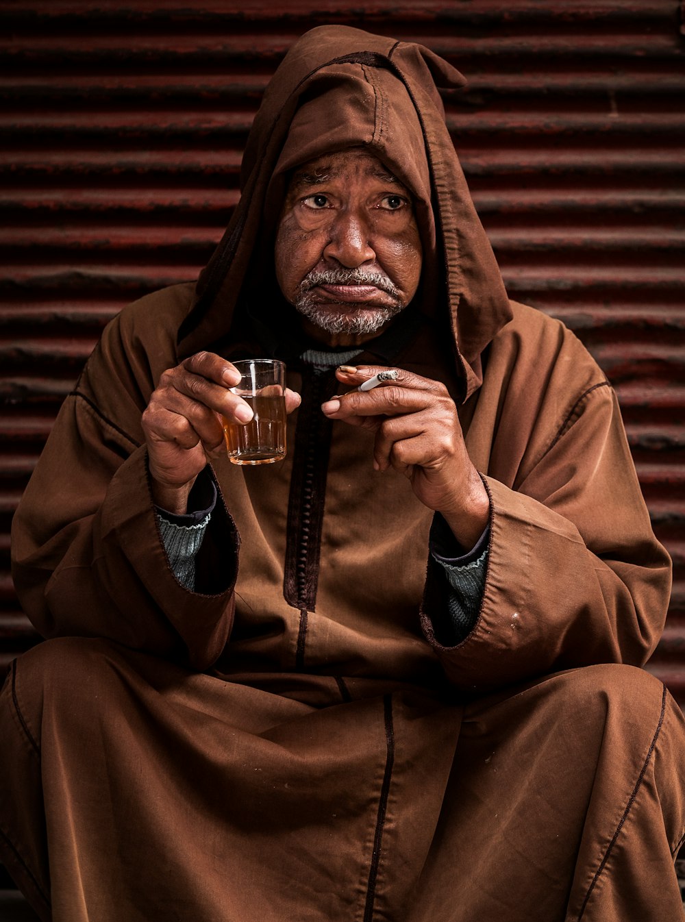 man wearing cloak and holding drinking glass